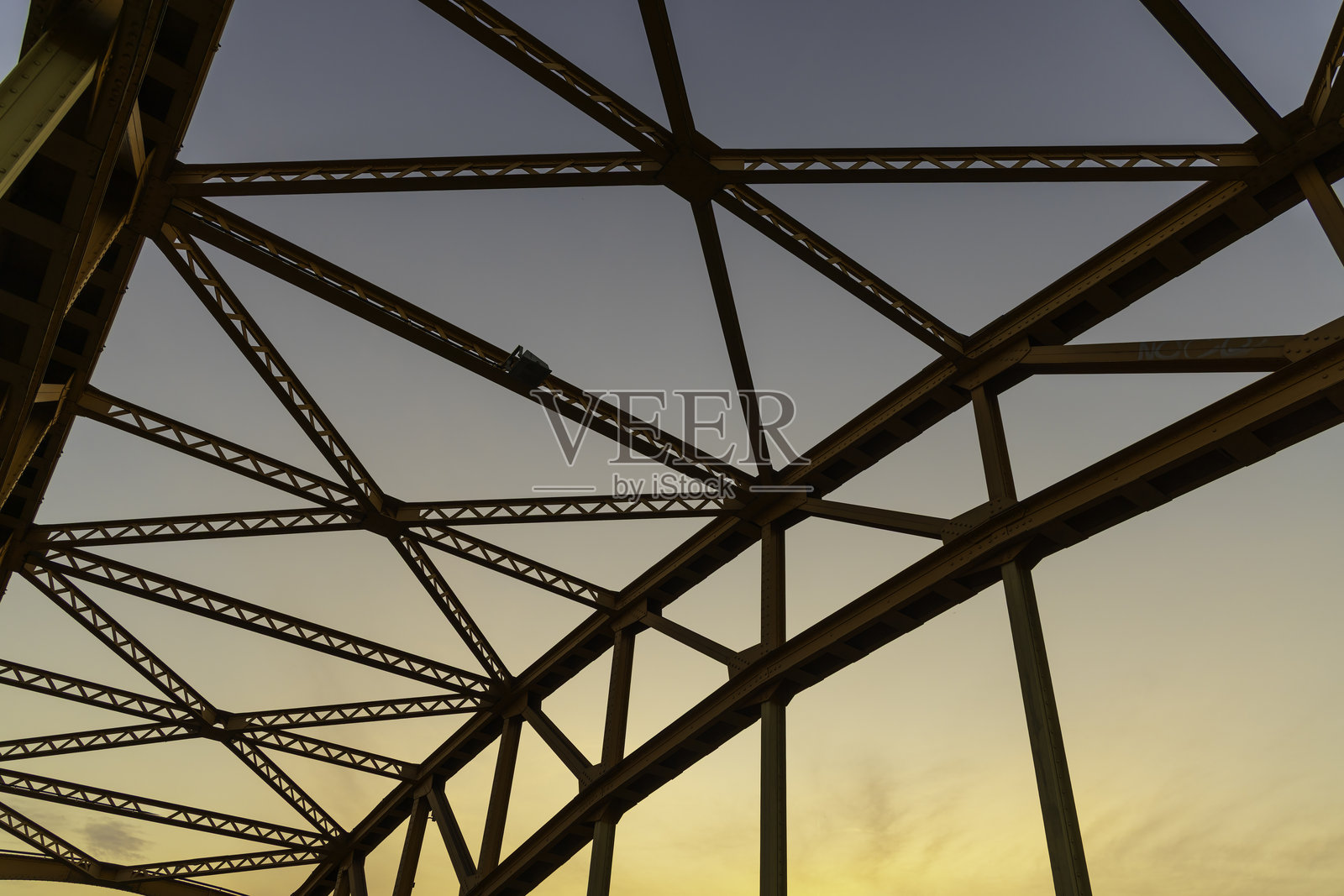 金属桥梁结构在清晨的阳光下展现出复杂的设计和工程，突显了所涉及的工艺。照片摄影图片