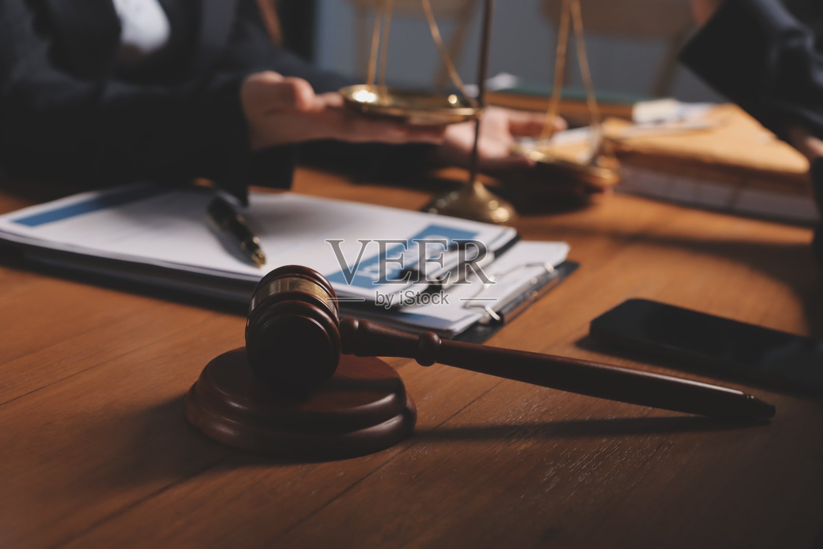 吸引人的年轻律师在办公室里，商务女性和律师们正在讨论合同文件，木桌上放着铜天平。法律、法律服务、咨询、正义和房地产概念。照片摄影图片