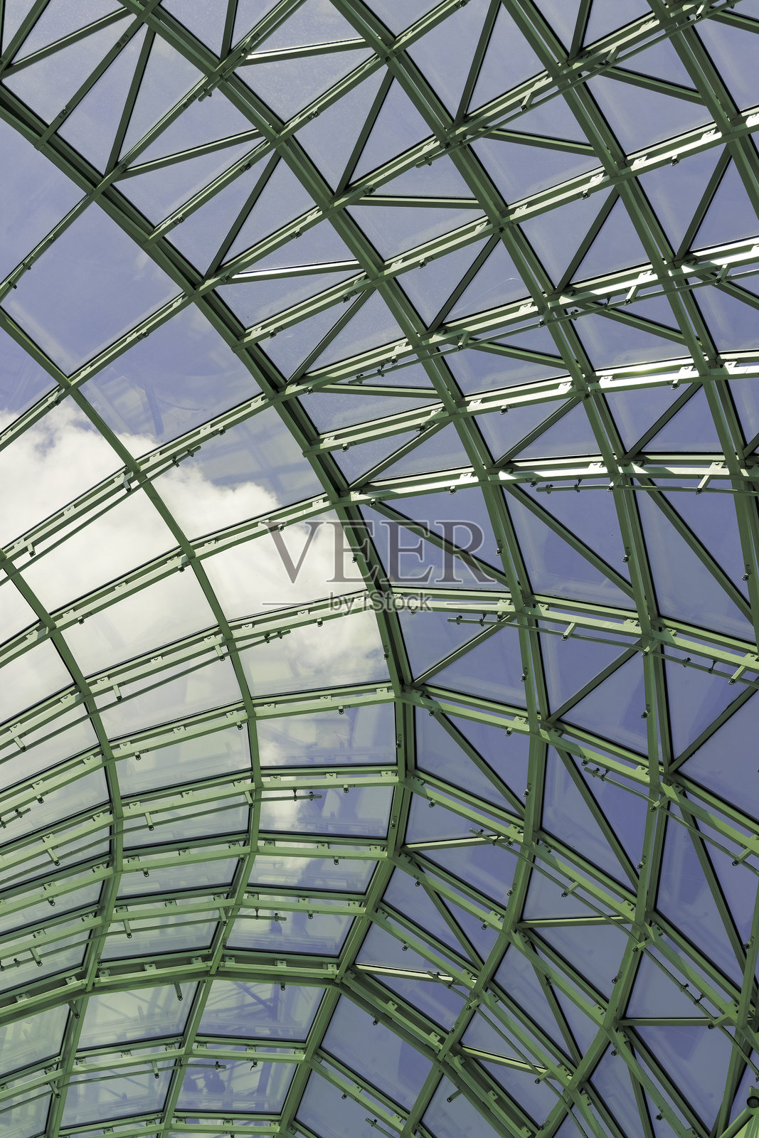 现代玻璃屋顶结构，配有复杂的金属框架，清澈的蓝天在城市环境中正午阳光下照耀。照片摄影图片