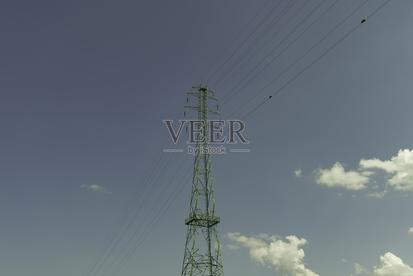 高压电线在白天的乡村地区横跨天空，展示了电力传输的基础设施。照片摄影图片