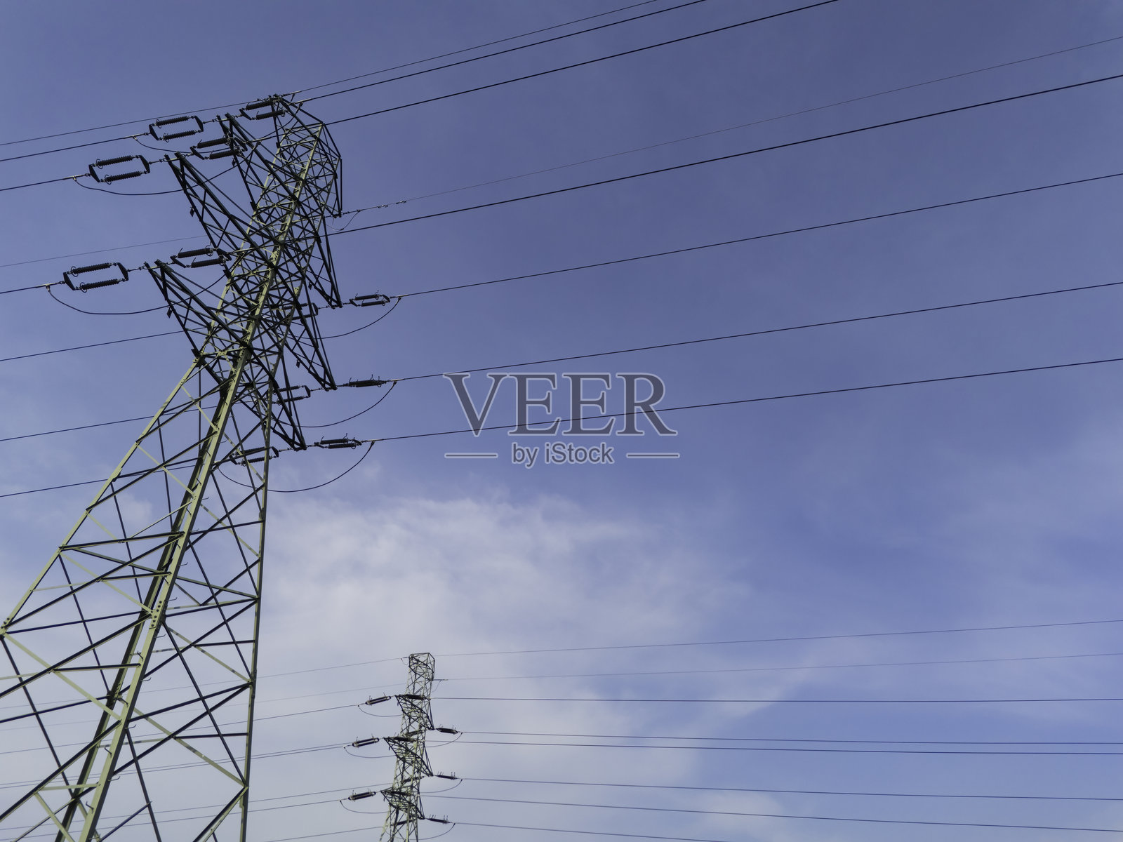 高压电线在白天的乡村天空中延伸，展示了电力传输的基础设施。照片摄影图片