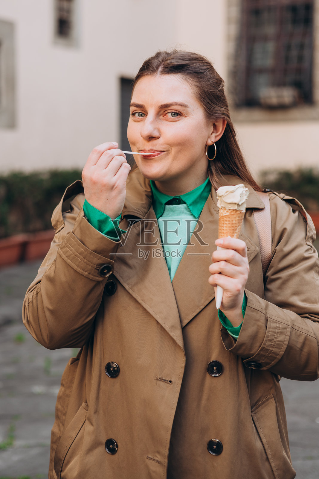 美味的开心果冰淇淋蛋筒在手中。特写镜头展示女性手握新鲜华夫饼筒，里面装着粉色冰淇淋。户外，意大利美食，生活方式，旅行，人物概念。照片摄影图片