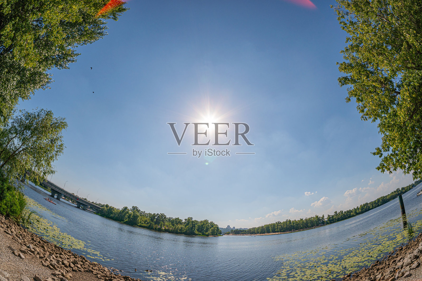 宁静水域的全景照片，四周环绕着自然，拍摄于白天，天空晴朗，阳光明媚。照片摄影图片