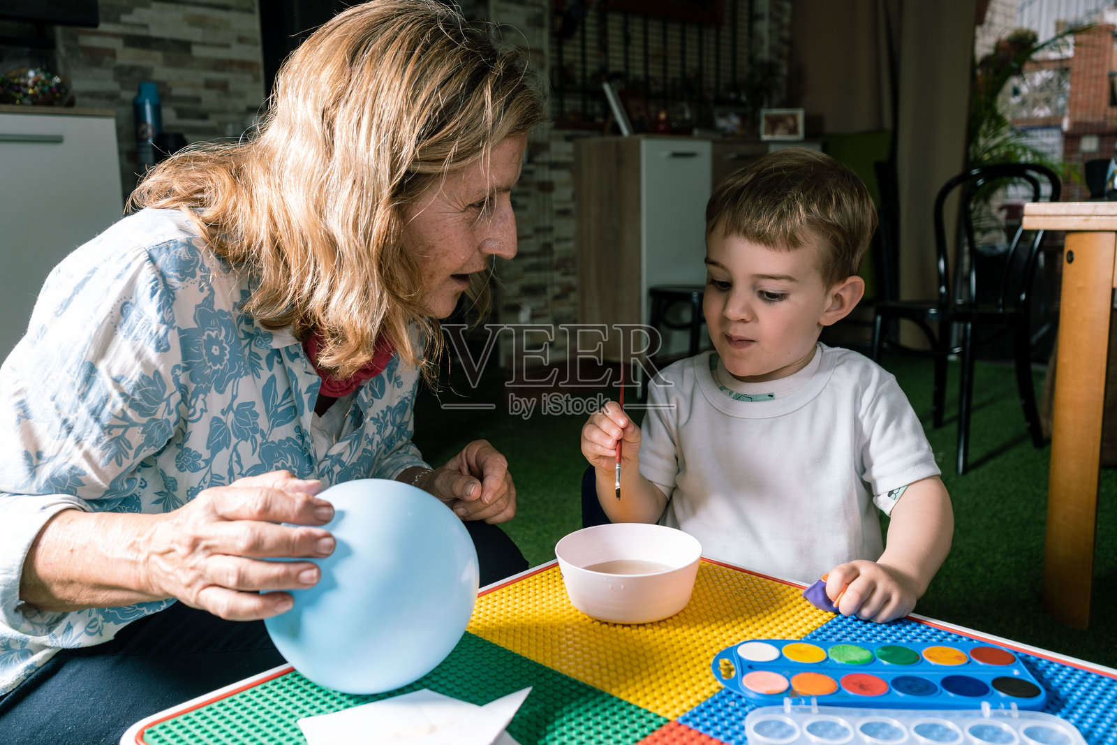 祖母帮助孙子用水彩在气球上绘画照片摄影图片