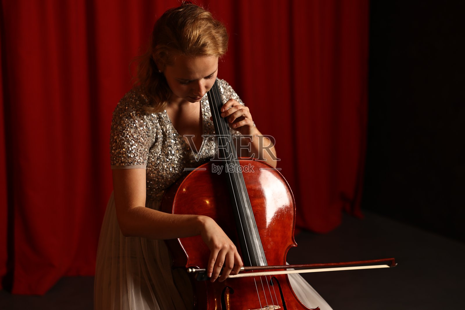 美丽的年轻女性在舞台上演奏大提琴照片摄影图片