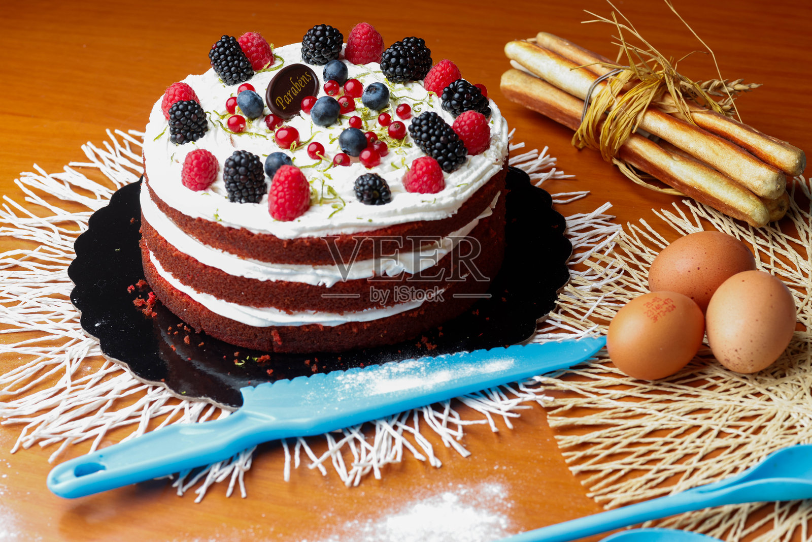 木桌上的奶油浆果蛋糕与烘焙工具照片摄影图片