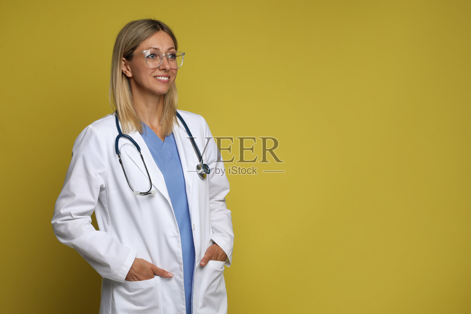 穿着医疗制服的医生肖像，佩戴听诊器，背景为黄色，留有文字空间照片摄影图片