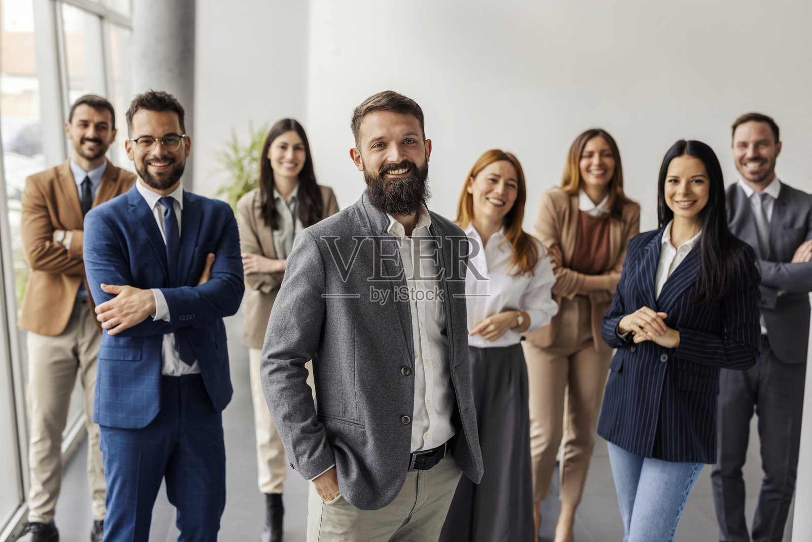 成功领导者与性别平衡的团队站在一起，面带微笑地看向镜头。照片摄影图片