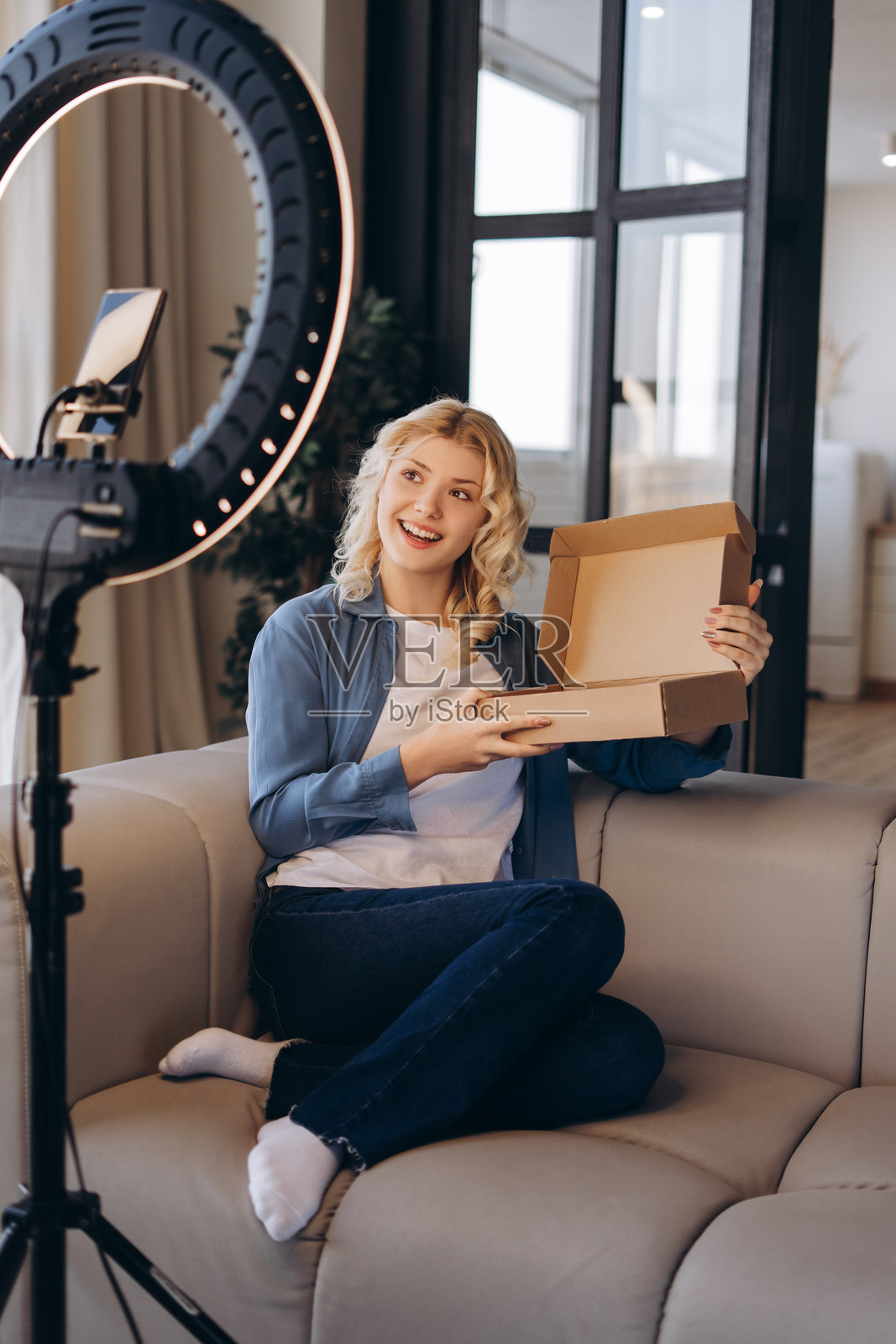 微笑的年轻青少年在家里的沙发上录制开箱新衣服的视频照片摄影图片
