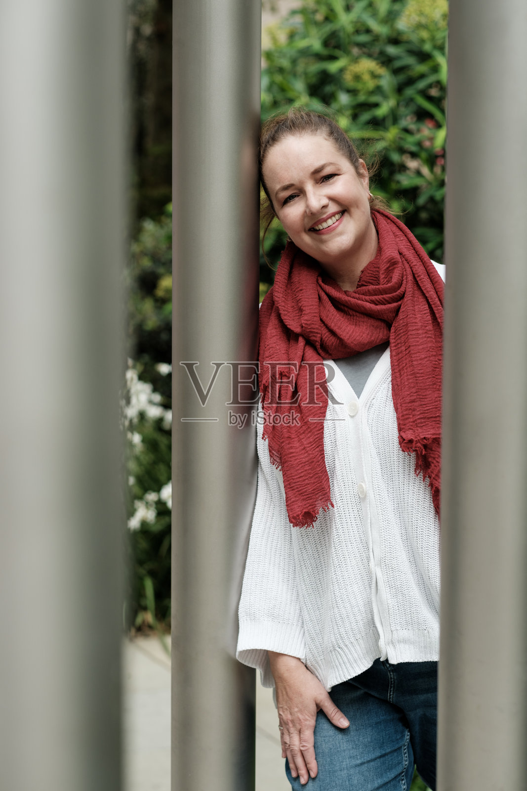 微笑的女性靠在城市环境中的金属柱子上照片摄影图片