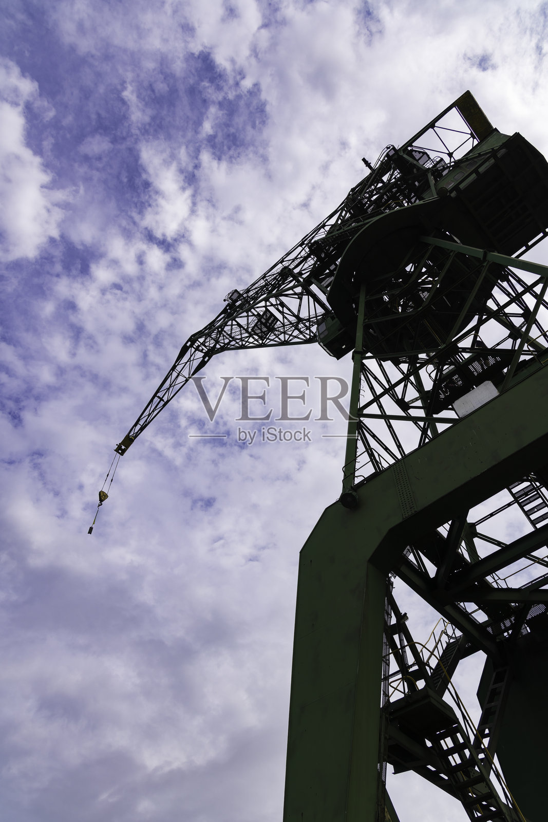 大型工业起重机矗立在繁忙城市区域的建筑工地上，背景是晴朗的蓝天照片摄影图片