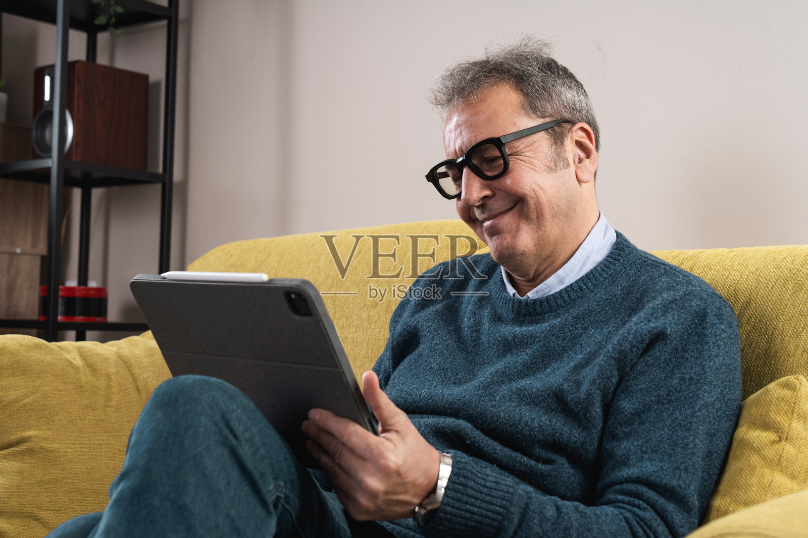 微笑的老年男子在家中使用平板电脑，享受数字内容照片摄影图片