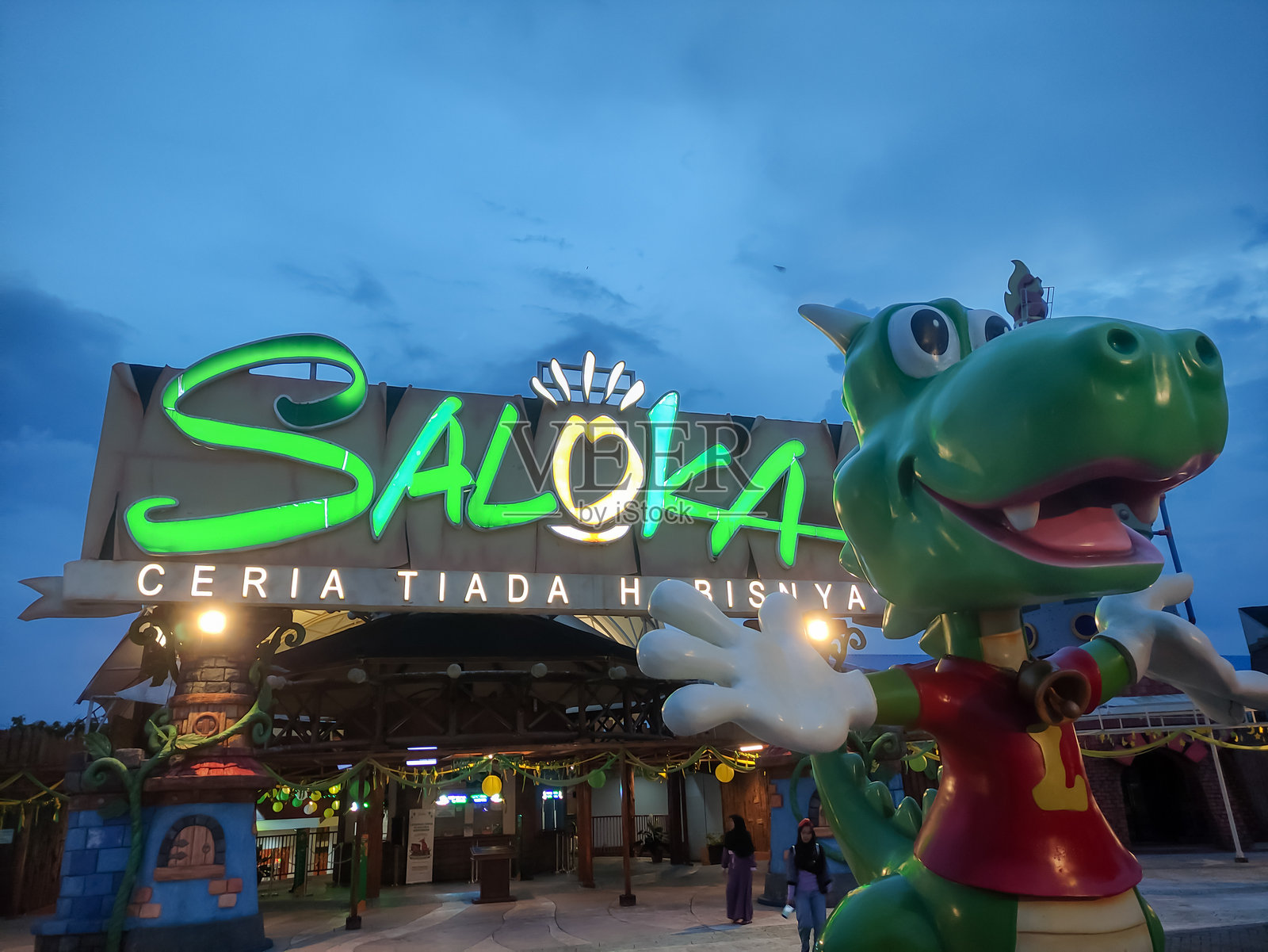 五彩斑斓的龙雕像俯瞰着萨洛卡游乐园入口，黄昏时分。照片摄影图片