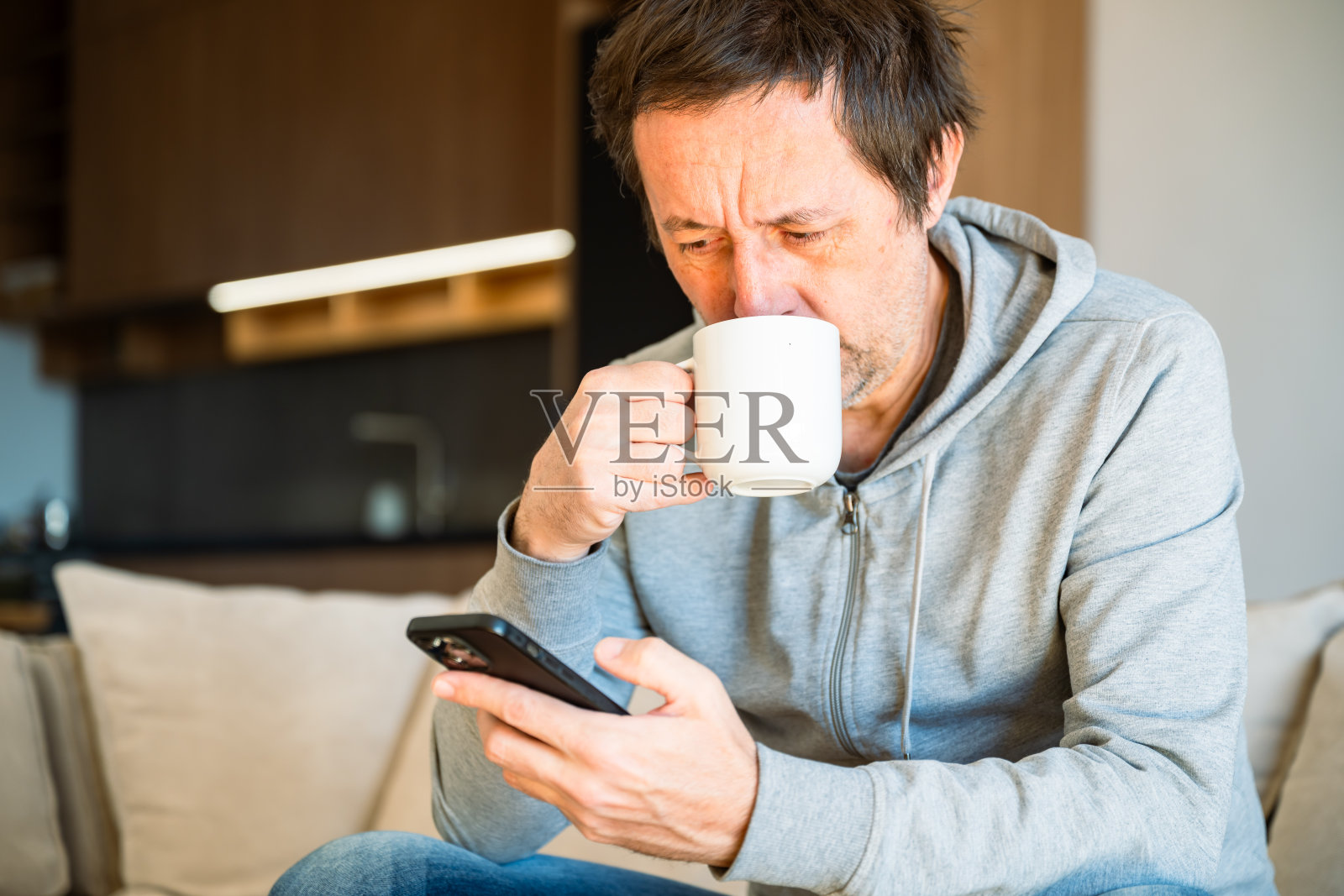 男人在早晨的家中喝咖啡并使用手机照片摄影图片