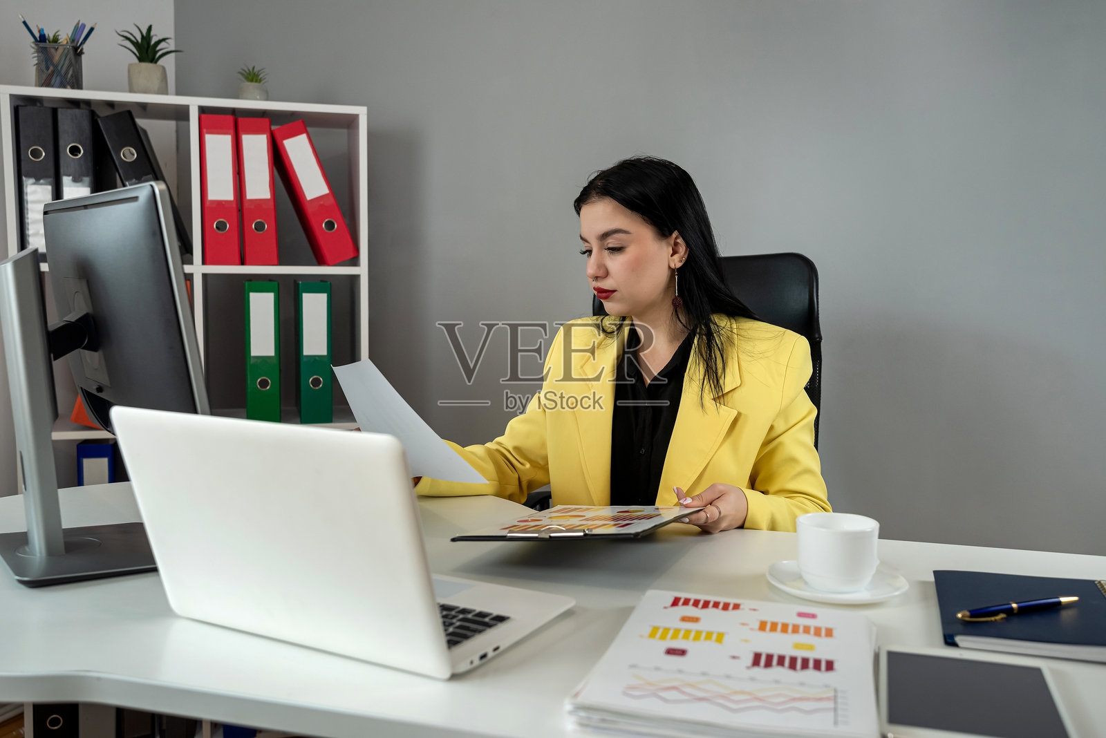 美丽的年轻女商人在办公室使用笔记本电脑处理财务文件照片摄影图片