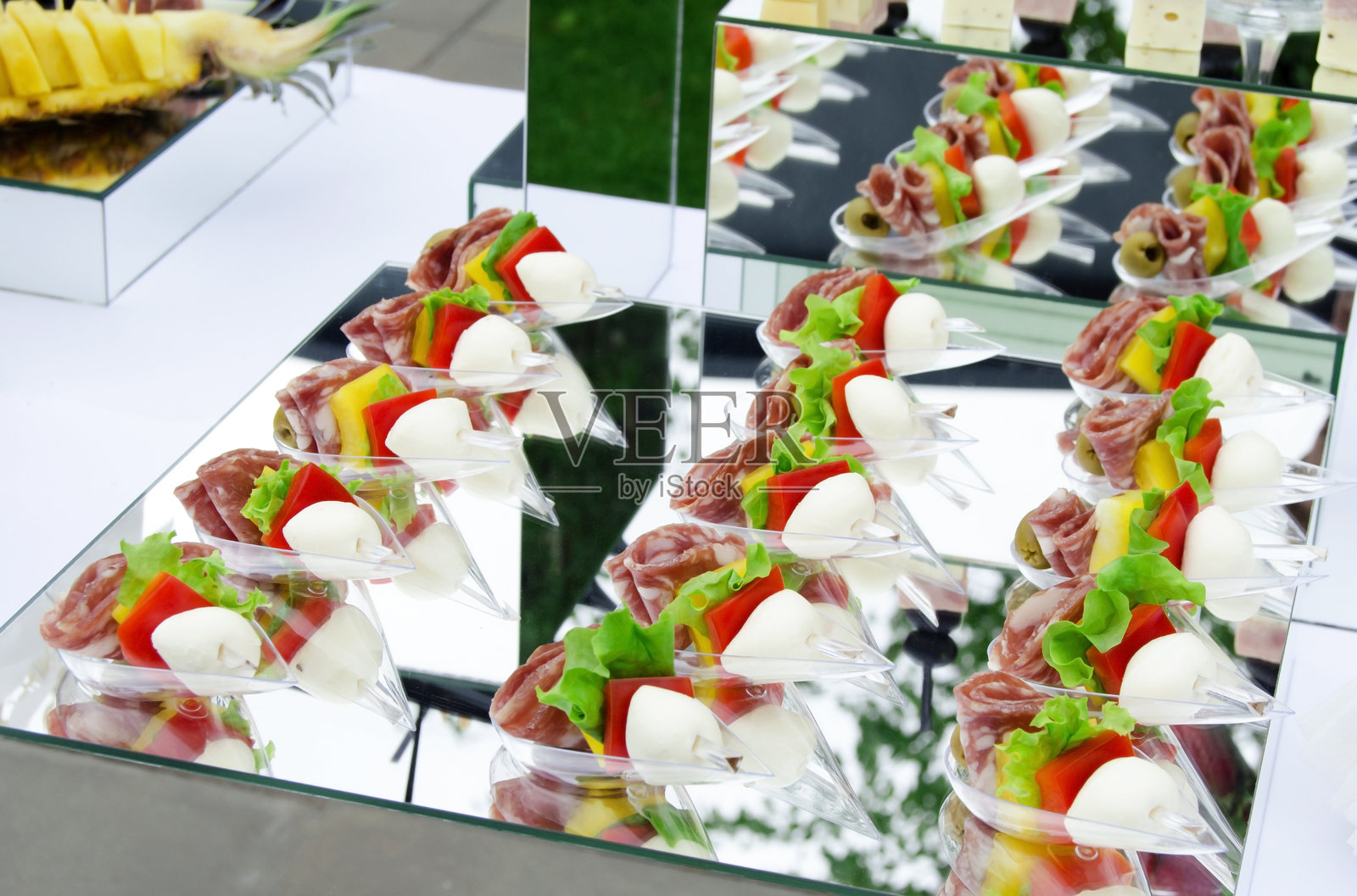 意大利风格的开胃菜，香肠、马苏里拉奶酪和番茄的卡普雷塞串，搭配罗勒。精美装饰的宴会餐饮桌。企业生日派对活动或婚礼庆典。照片摄影图片