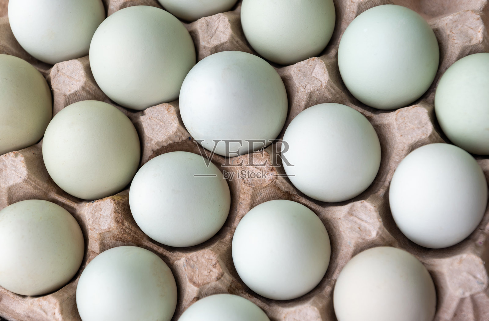 整齐排列在棕色回收纸蛋 carton 中的浅蓝色和绿色的阿拉卡纳鸡蛋，概念新鲜，健康食品，随时可食用照片摄影图片