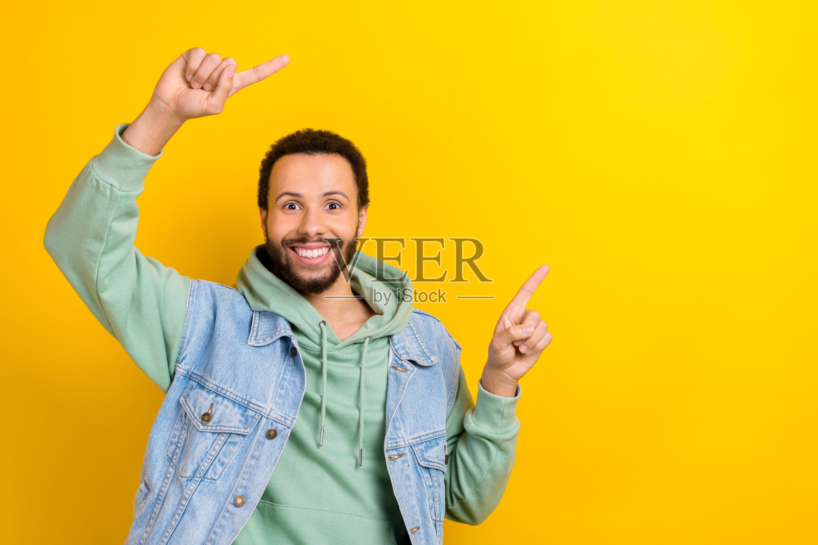 面带灿烂笑容的愉快男士，手指指向空白处，适合新闻广告，背景为黄色。照片摄影图片