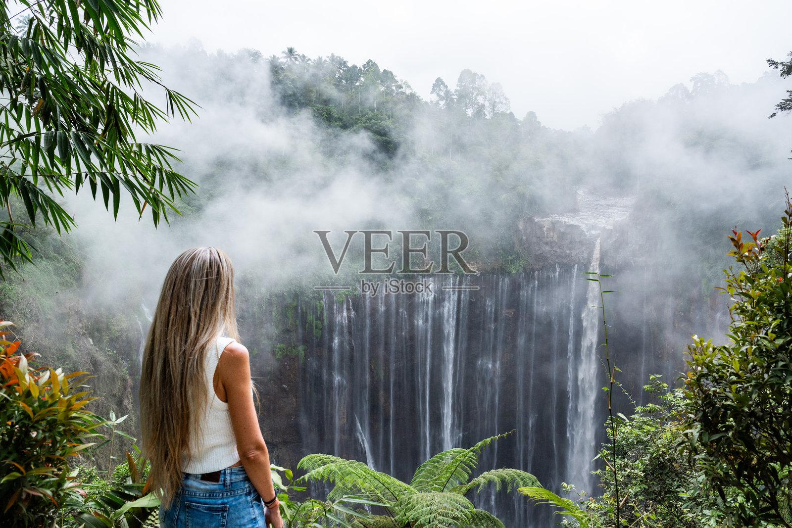 游客女性在印度尼西亚爪哇岛欣赏壮丽的图姆帕克塞武瀑布照片摄影图片