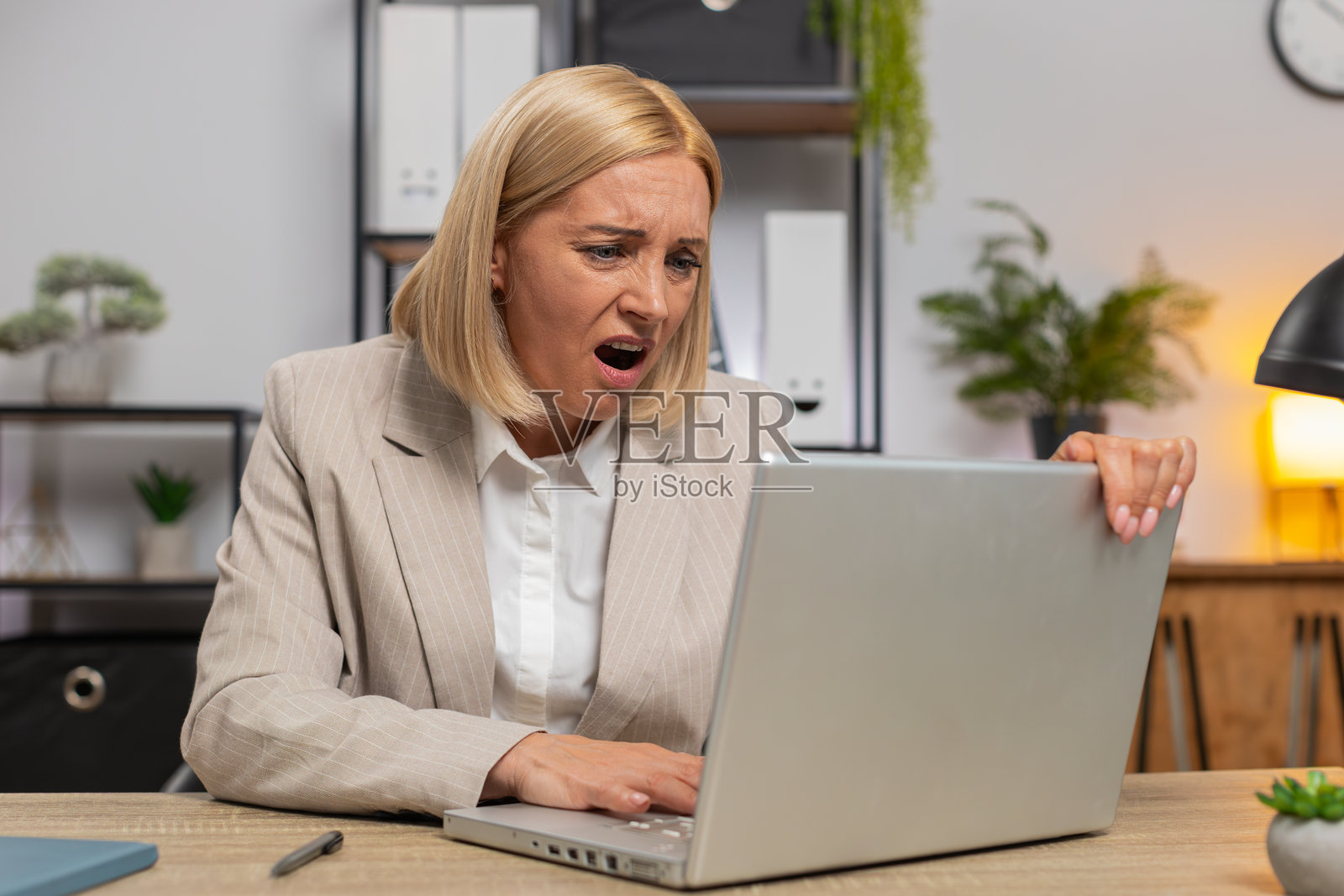 不满的伤心女商人使用笔记本电脑，惊讶于彩票结果和电脑病毒的坏消息照片摄影图片