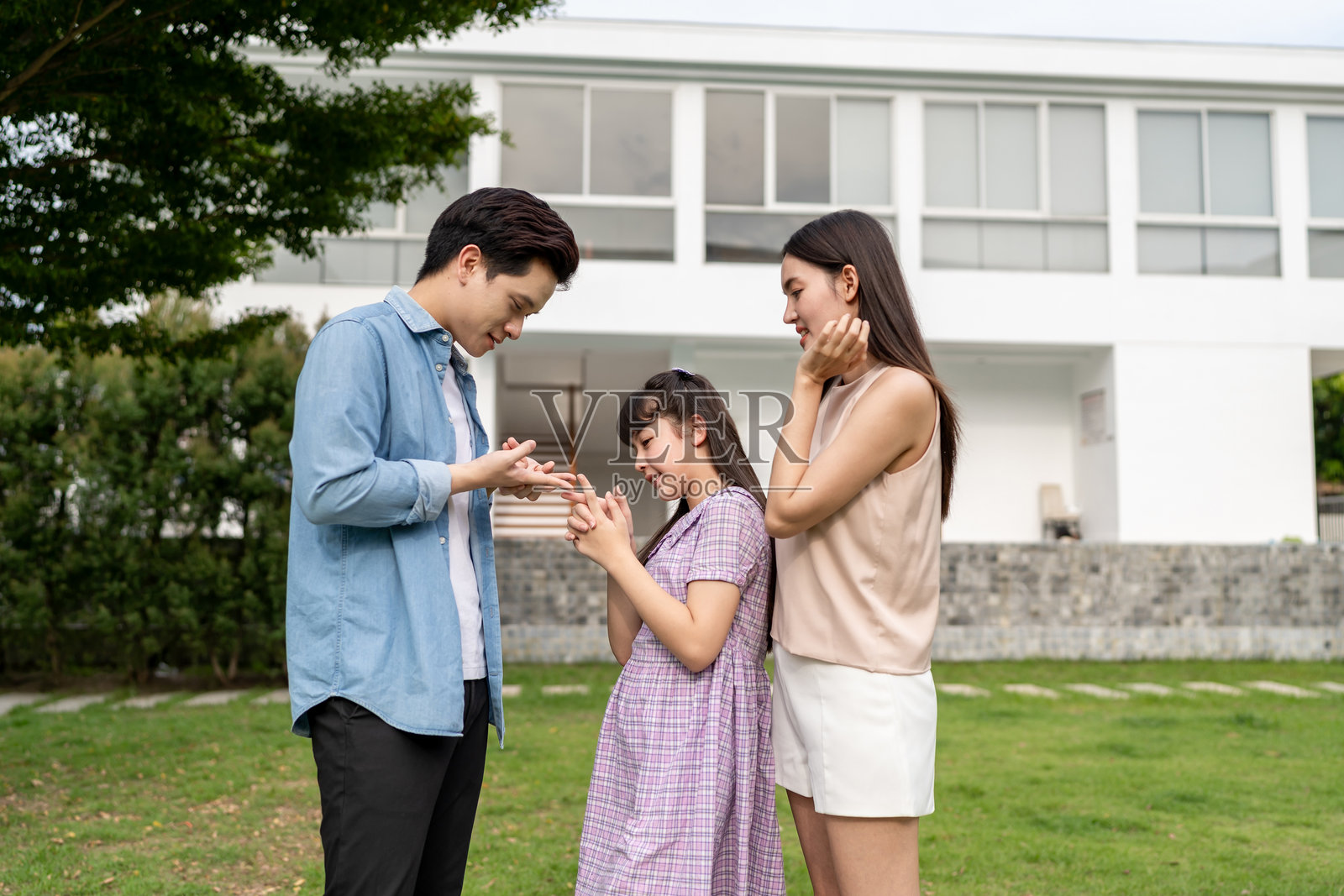 亚洲父母在花园里与小女儿玩耍。幸福的家庭，迷人的夫妻和小女孩在家后院放松并享受共度时光。家庭关系概念照片摄影图片