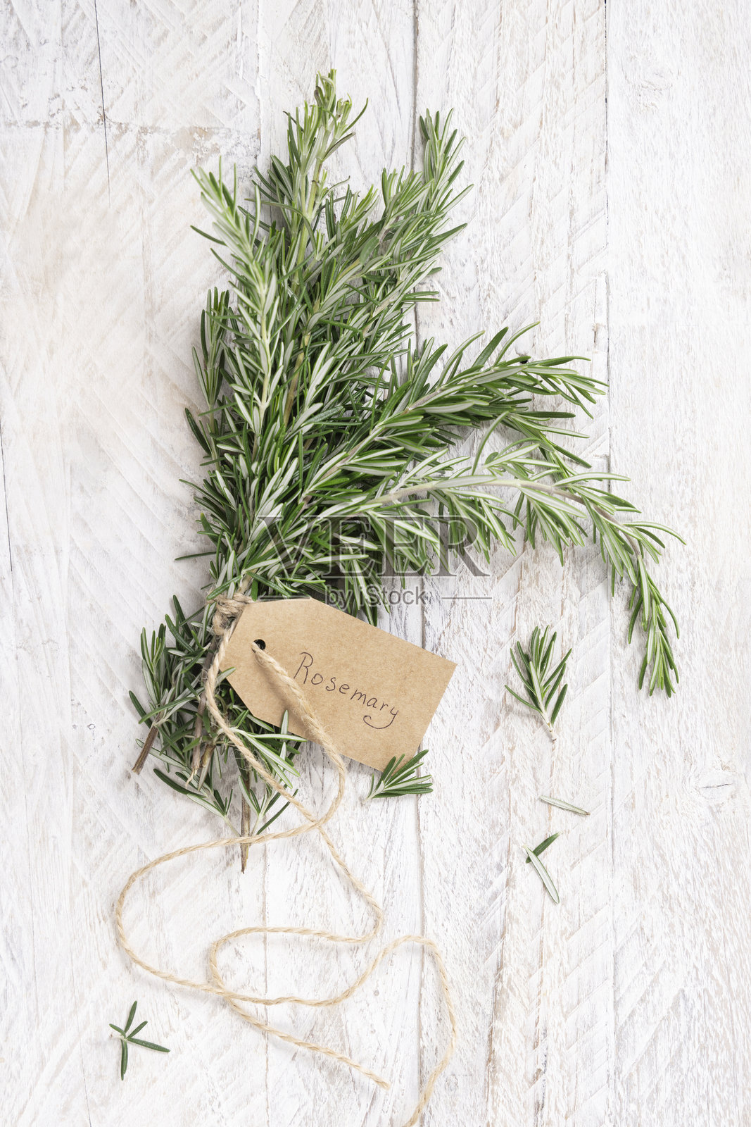 新鲜的绿色迷迭香枝条，带有牛皮纸标签，放在白色风化木桌面上俯视图照片摄影图片