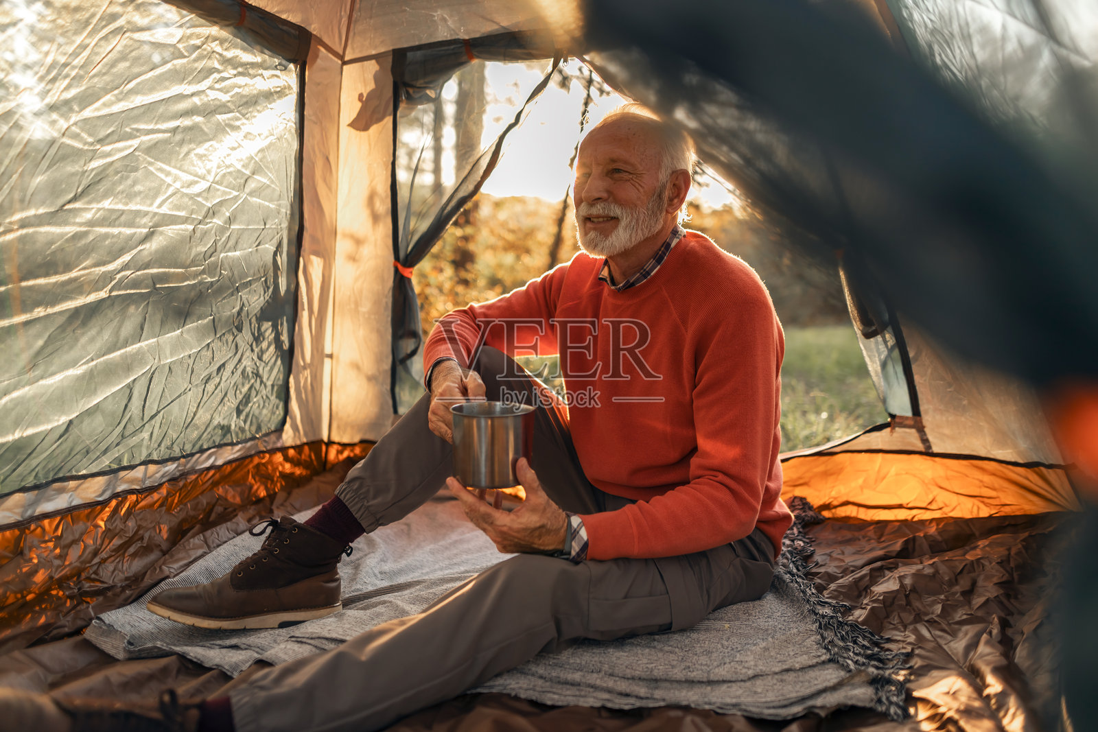 老年人在日落时分的帐篷中放松，享受露营冒险照片摄影图片