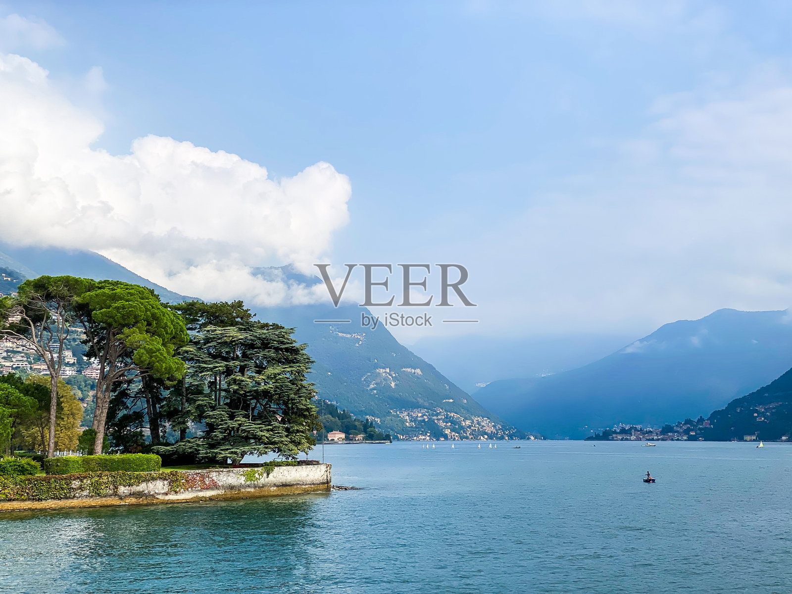 科莫湖的平静水面与远处的山脉照片摄影图片