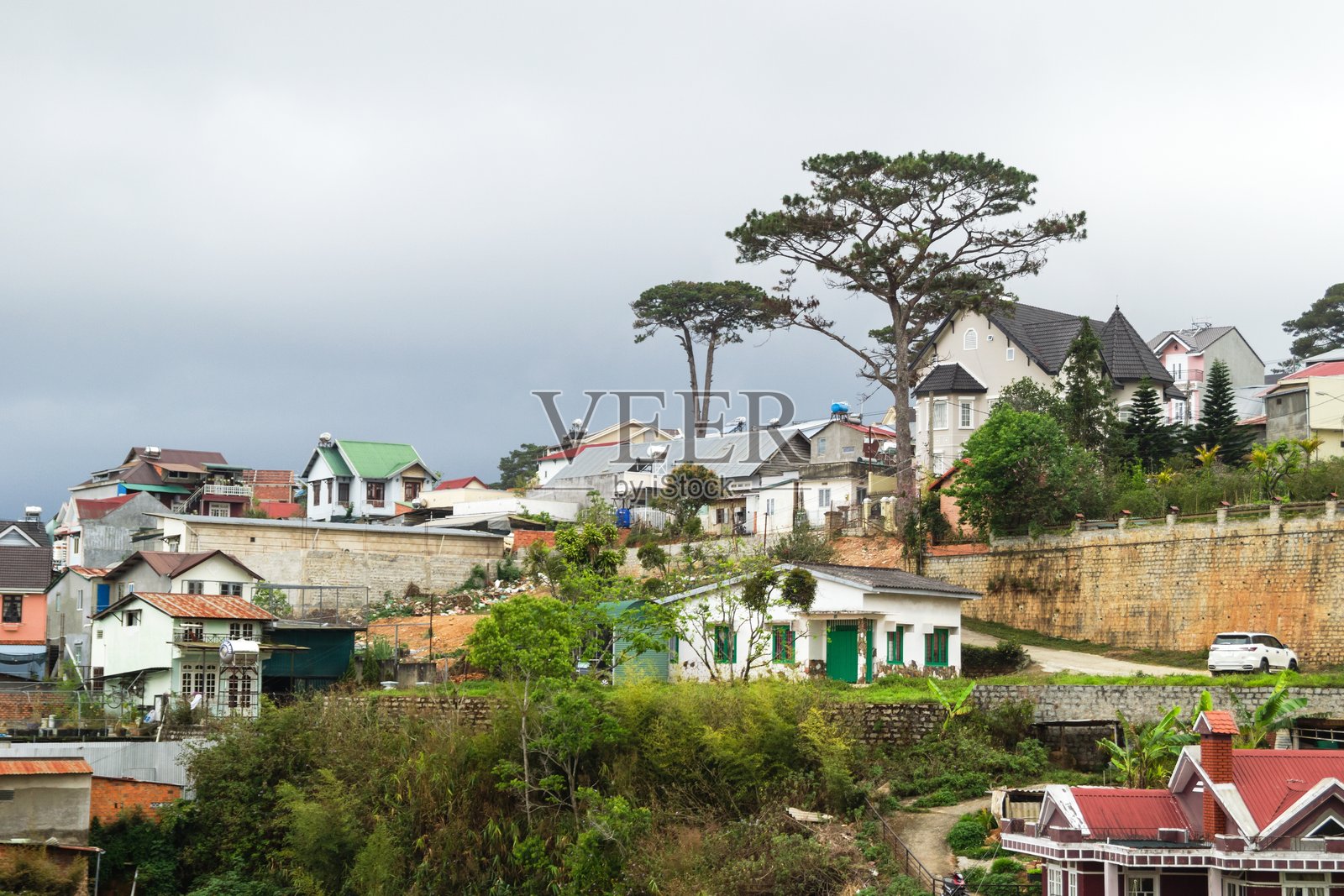 风景如画的山坡小镇，绿树成荫，房屋在多云的天空下。越南大叻。照片摄影图片