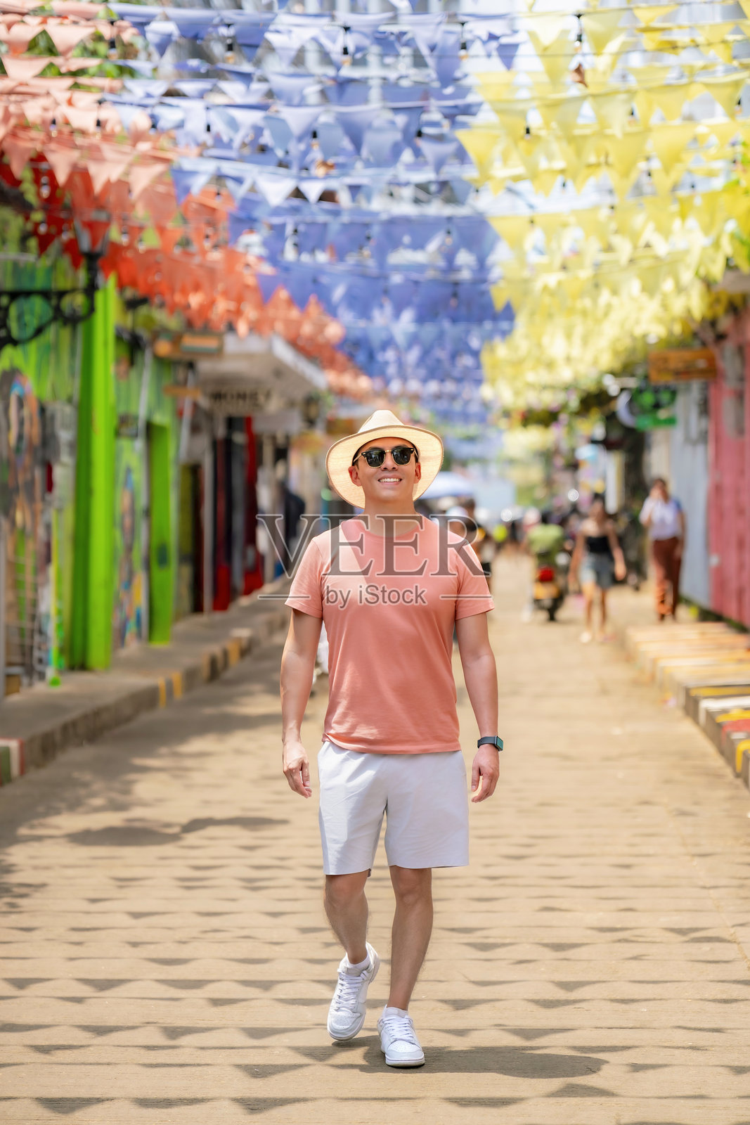 拉丁裔男子在卡塔赫纳的赫特塞马尼享受阳光明媚的日子，坐在纸伞下。照片摄影图片