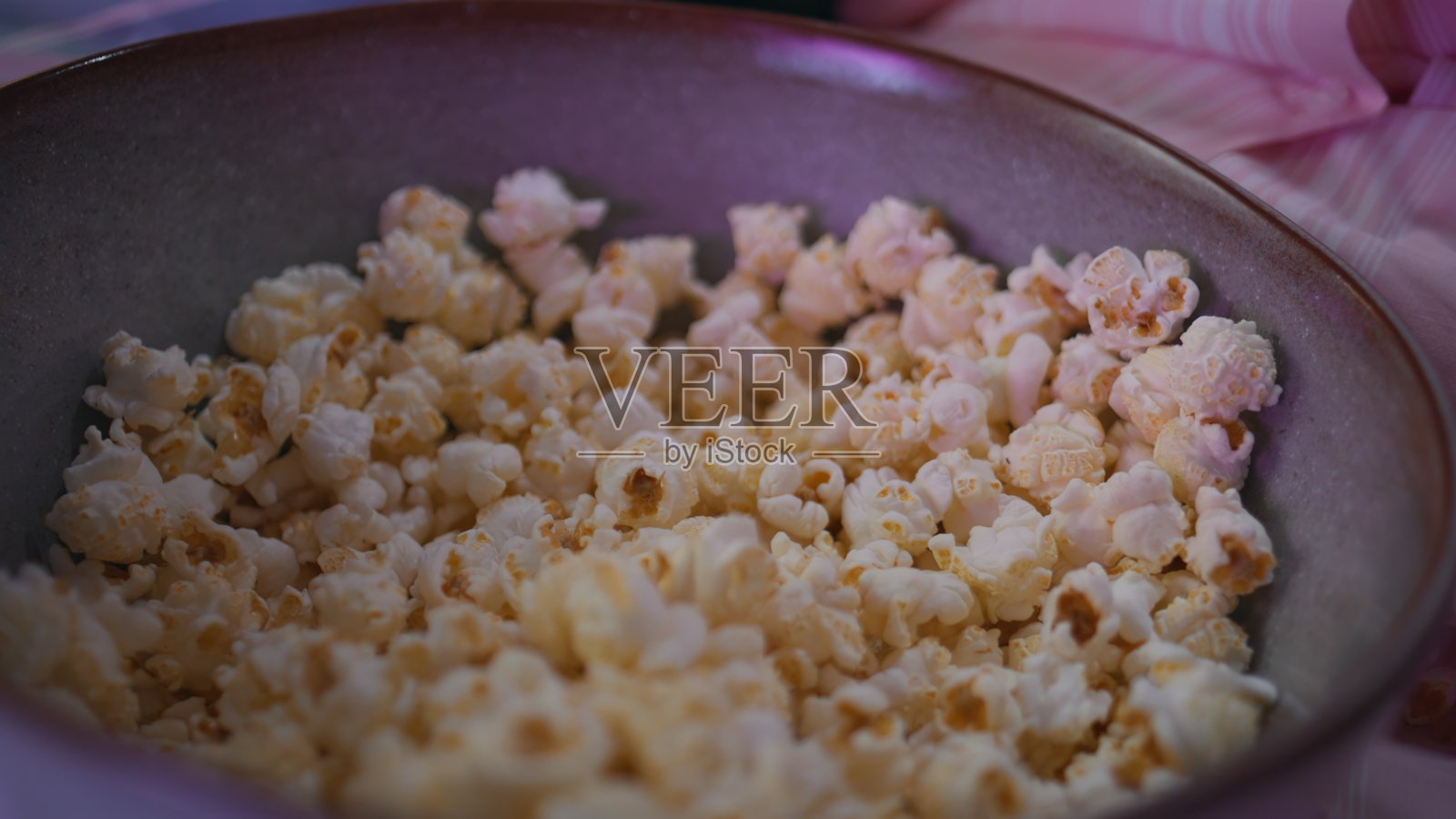 晚上在家中，特写镜头下的手从碗中取出爆米花，朋友们面目模糊。照片摄影图片