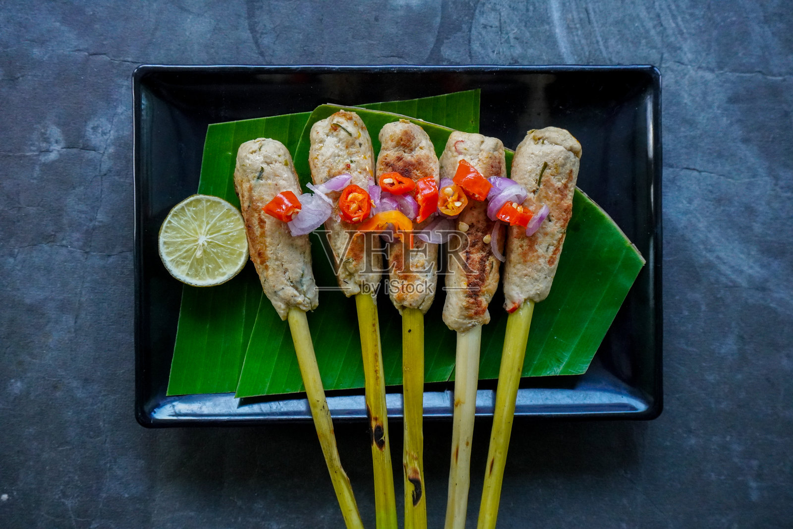 巴厘岛的椰浆串烧或椰浆串烧食品。串烧可以用鱼、鸡肉或牛肉制作，混合磨碎的椰子和浓厚的椰奶，包裹在香茅茎上。照片摄影图片