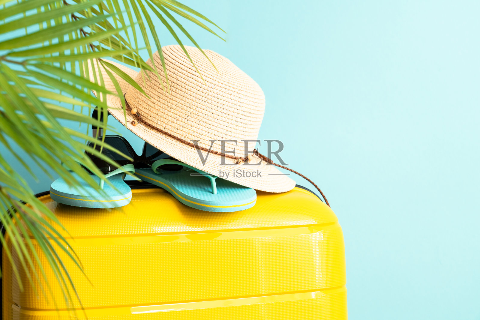 蓝色背景上的行李箱、帽子和人字拖。照片摄影图片