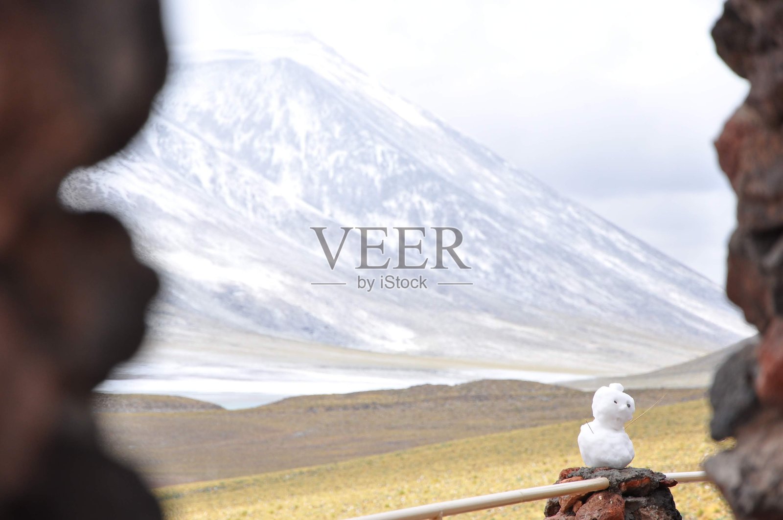 智利高原上的手工雪人，背景是雪-covered安第斯山脉照片摄影图片