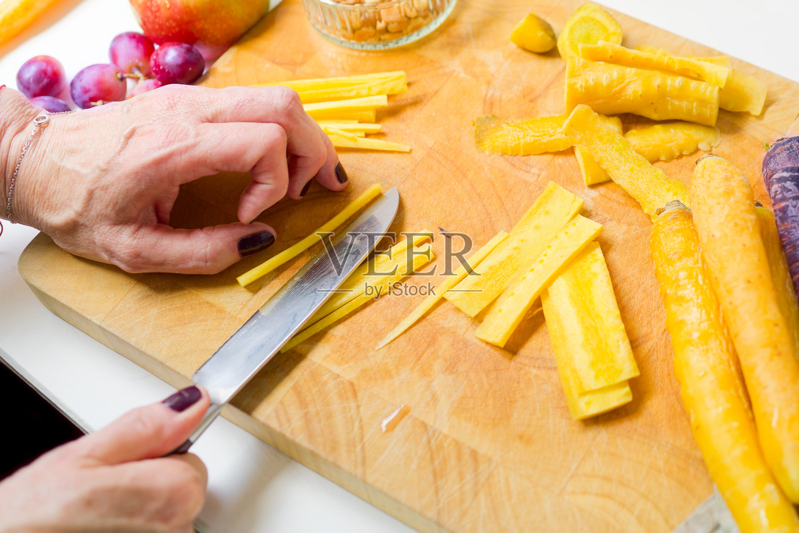 女人在切割板上切黄胡萝卜照片摄影图片