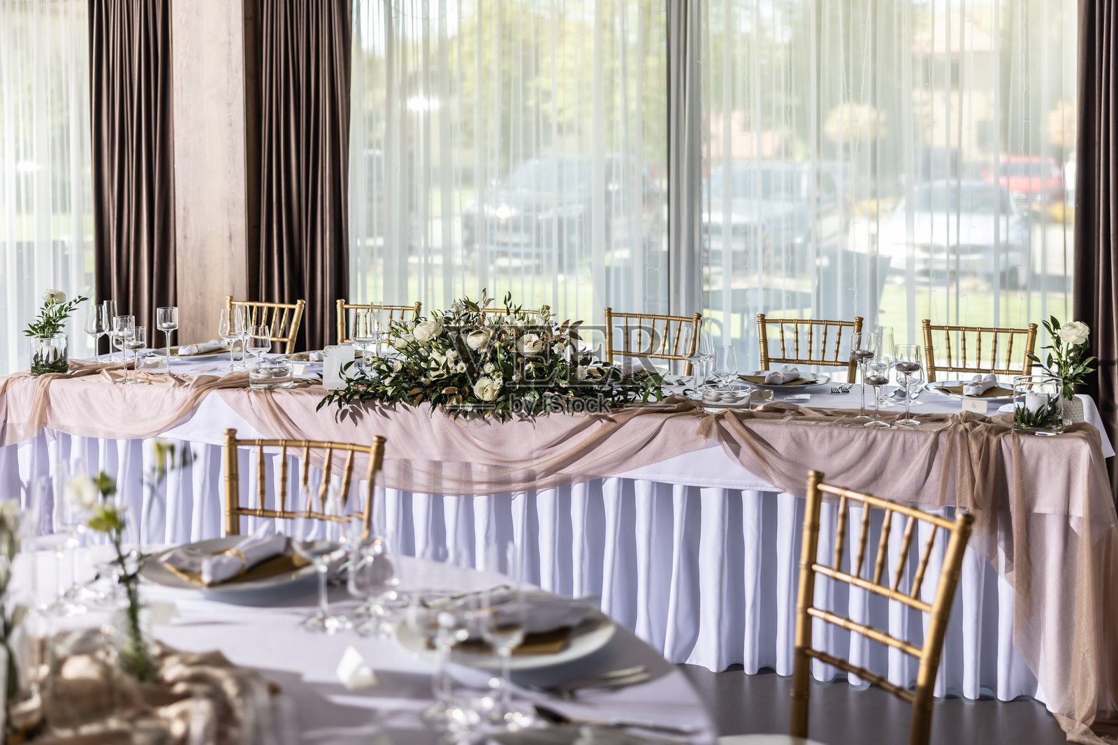 一张铺着白色桌布的婚礼桌，装饰着鲜花、蜡烛、酒杯和餐具照片摄影图片
