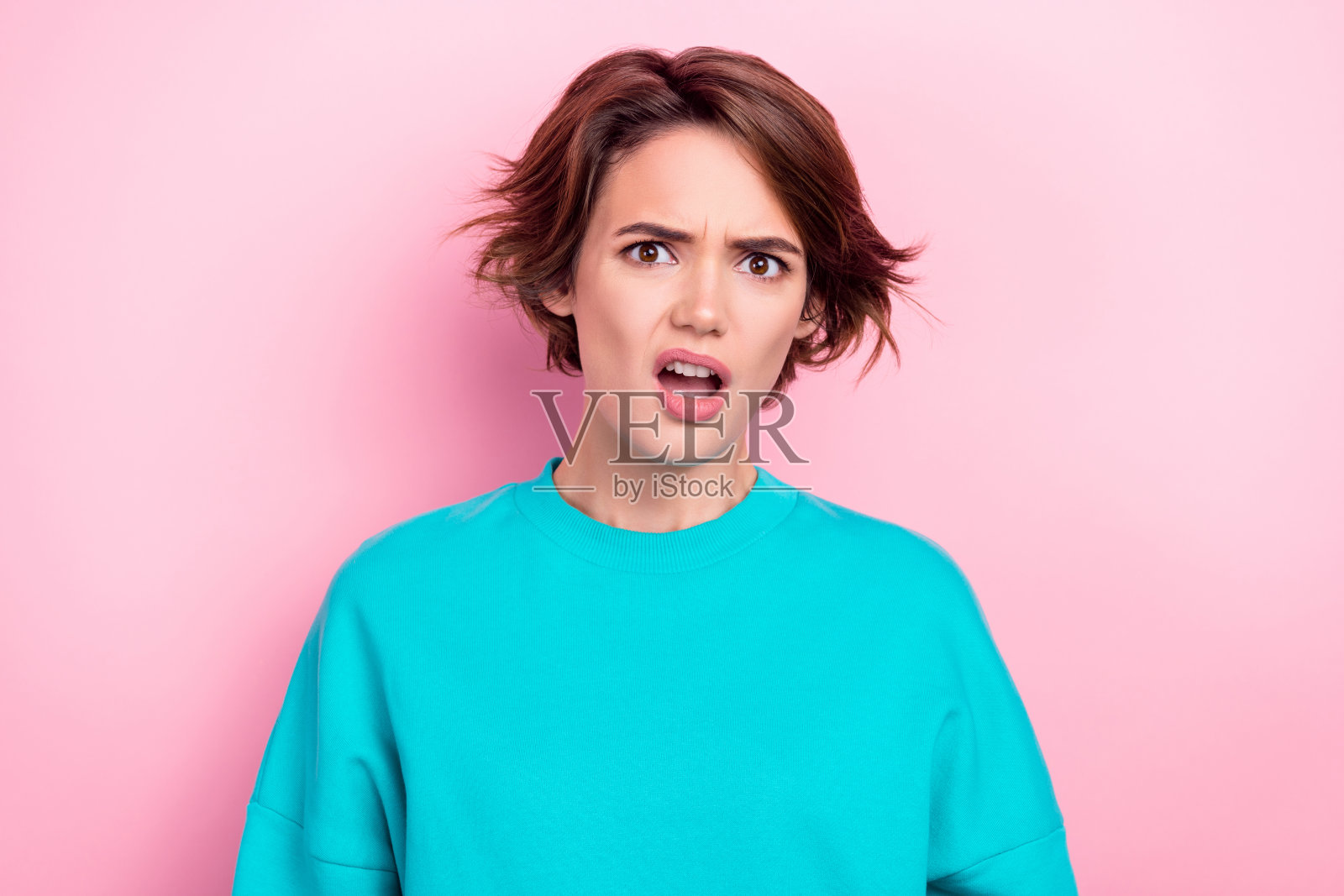 一位年轻漂亮的女士惊讶地张嘴，目光呆滞，困惑不解，背景为明亮的粉色。照片摄影图片