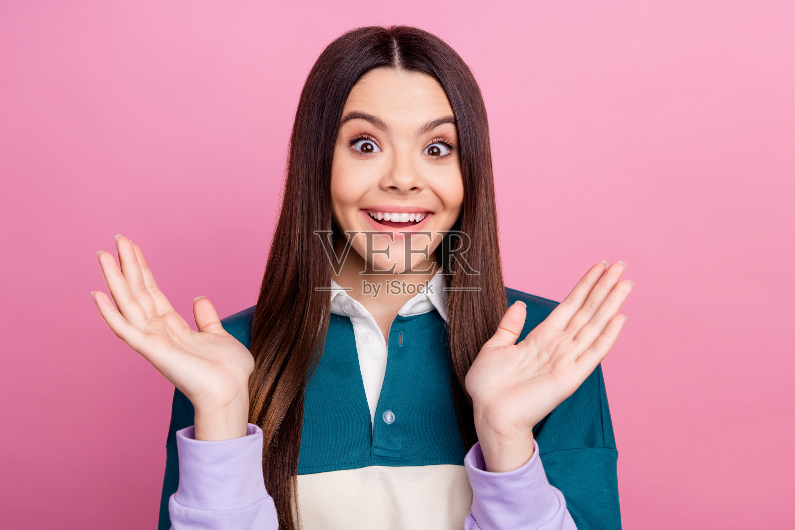 快乐的年轻女性，面带兴奋的表情，双手举起，背景为粉色。照片摄影图片