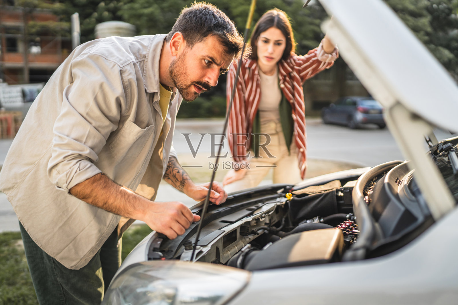 一对担忧的情侣站在街边的汽车旁，汽车的发动机故障了。照片摄影图片
