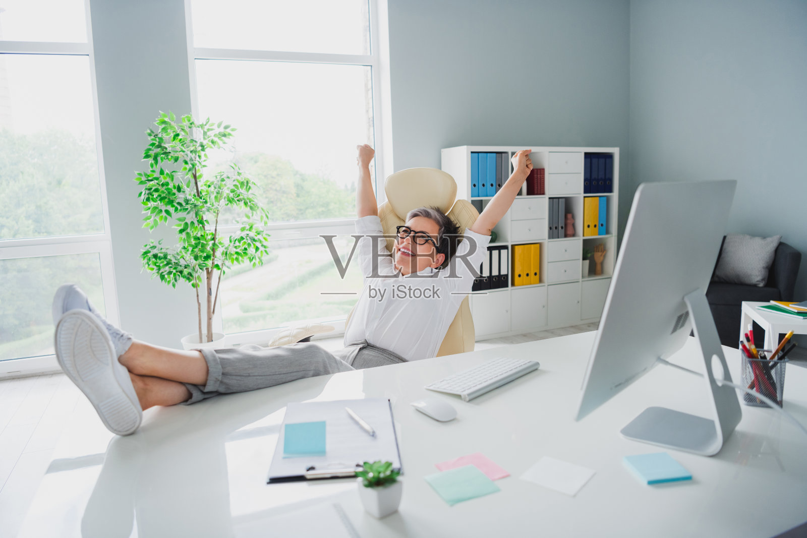 项目经理在办公室庆祝会议结束，双腿躺在桌面上，双拳举起的全身照片照片摄影图片