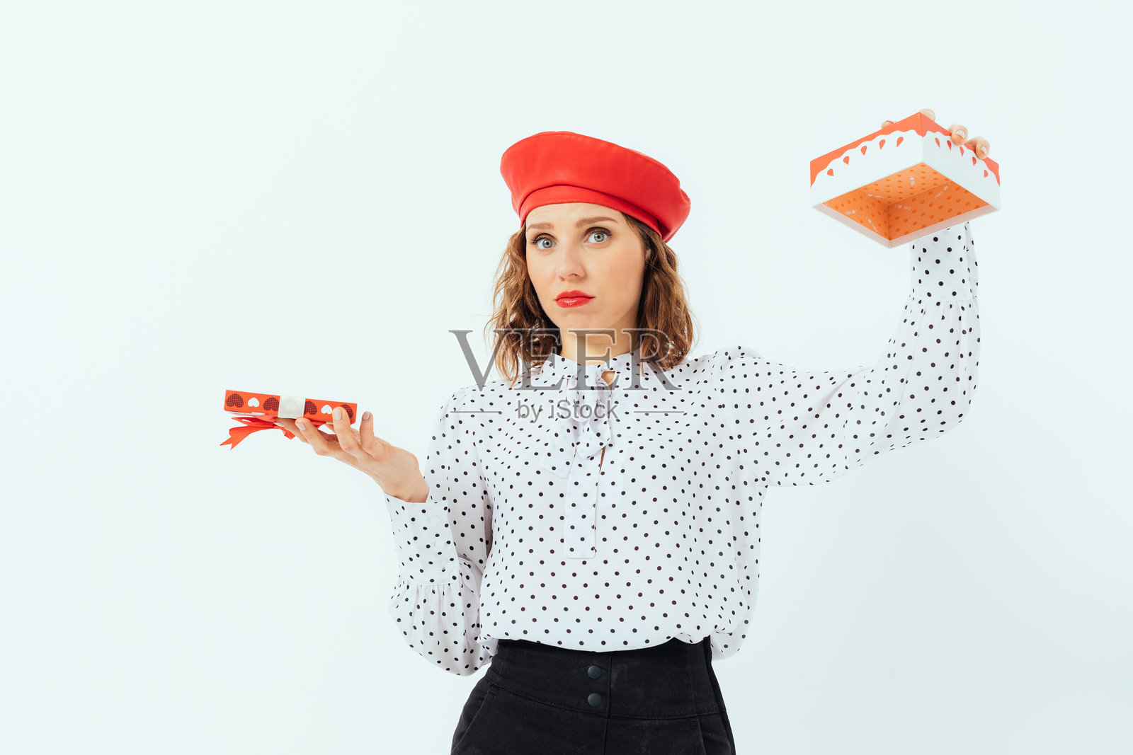 一位戴着红色帽子的女人手里拿着一个空礼品盒。照片摄影图片