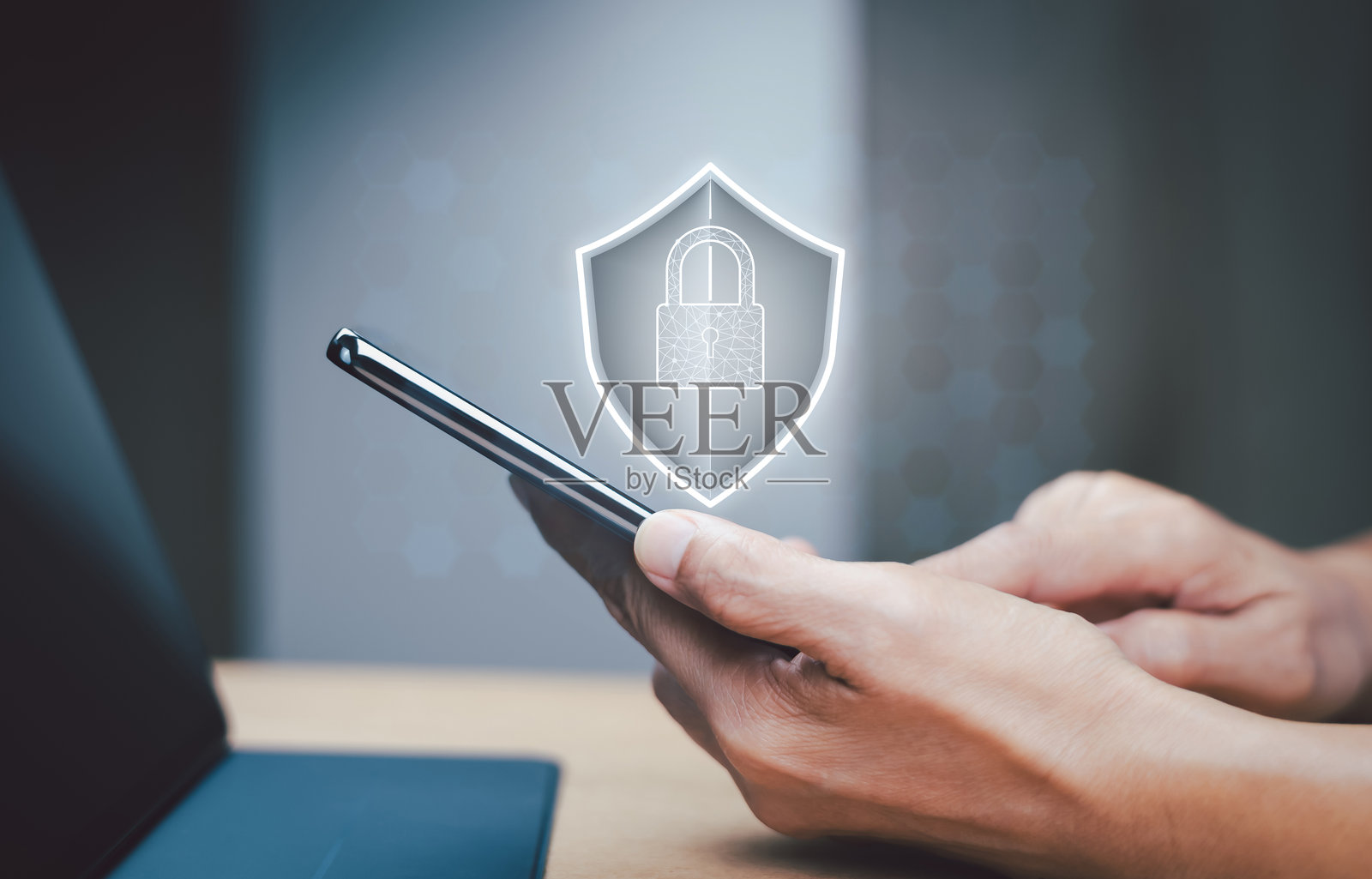 手持智能手机，屏幕上显示锁图标，登录前需要密码认证，办公桌上的场景。个人信息安全。网络安全，数据保护概念。照片摄影图片