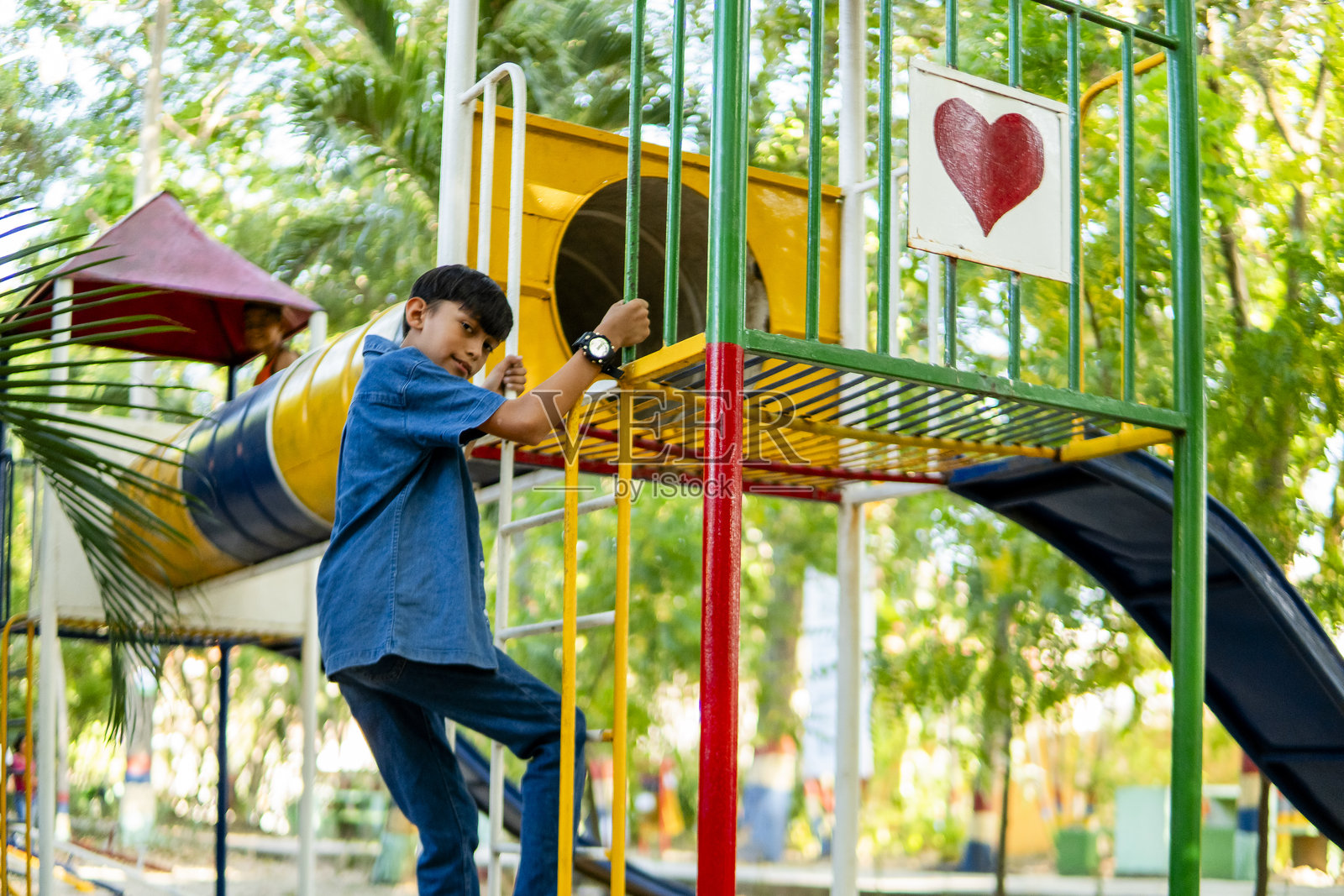 小学孩子在公园的五彩斑斓的游乐设施上攀爬照片摄影图片