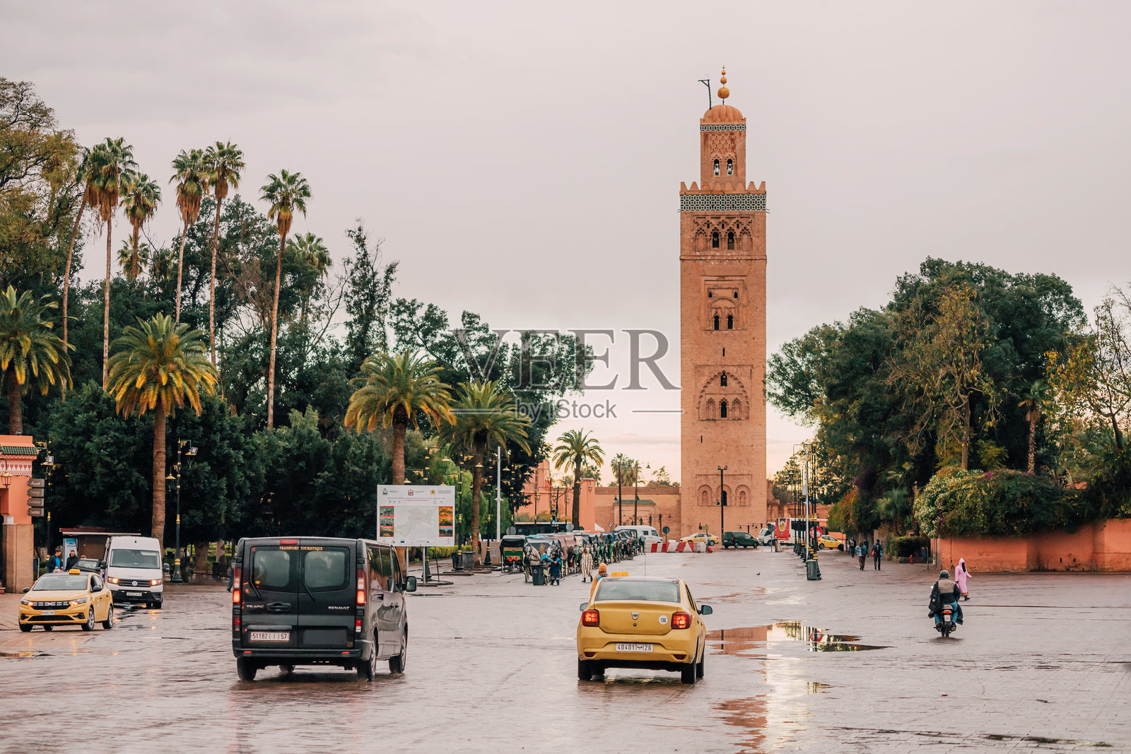 汽车在湿滑的道路上行驶,库图比亚清真寺的宣礼塔在繁忙的广场上高耸。照片摄影图片