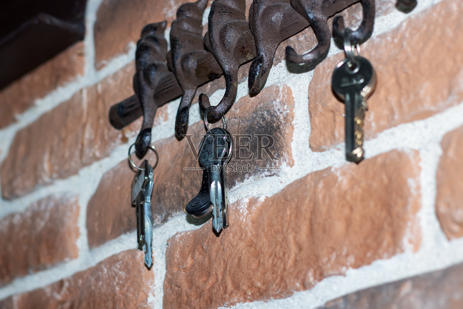 一串钥匙悬挂在砖面上的钩子上照片摄影图片