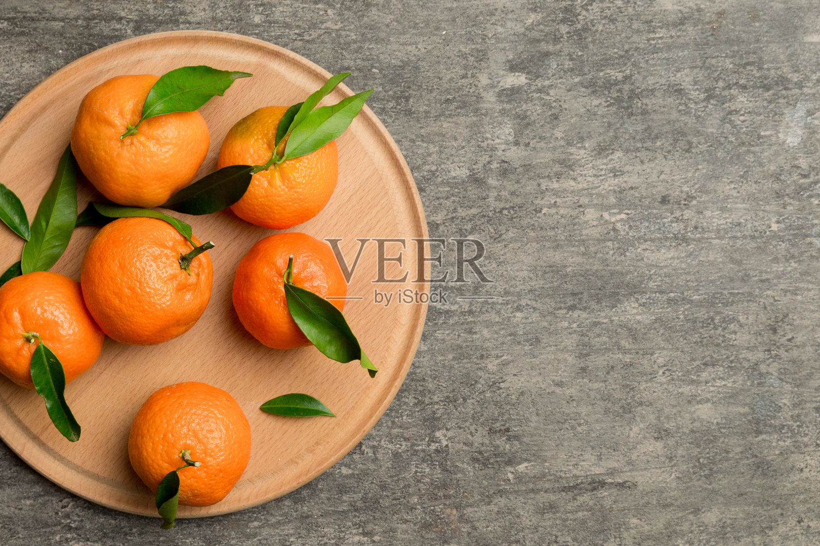 新鲜切好的克莱门丁和整颗橘子放在圆盘上，背景色彩丰富。食材准备，健康饮食主题的俯视图，留有空白空间。照片摄影图片