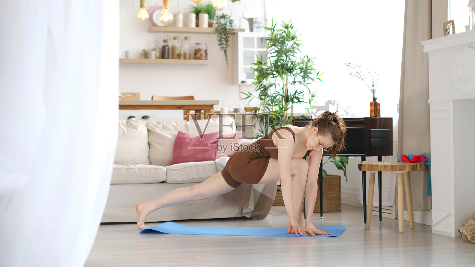 一位女性在舒适的客厅中练习一个具有挑战性的瑜伽姿势，强调力量和柔韧性。这个场景突显了居家锻炼的现代趋势，旨在促进整体健康。照片摄影图片