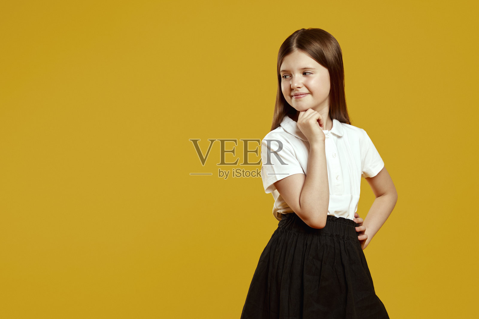 身穿校服的学生在黄色背景前愉快地摆姿势，目光投向空旷处。照片摄影图片