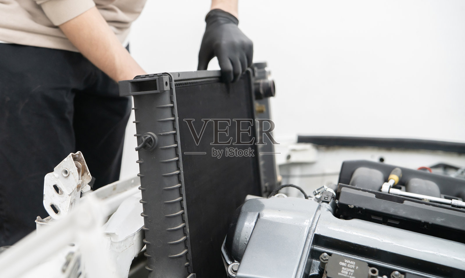 汽车修理工熟练地为车辆安装新的散热器，专注于确保合适的配合和功能，以实现有效的冷却系统运作。照片摄影图片