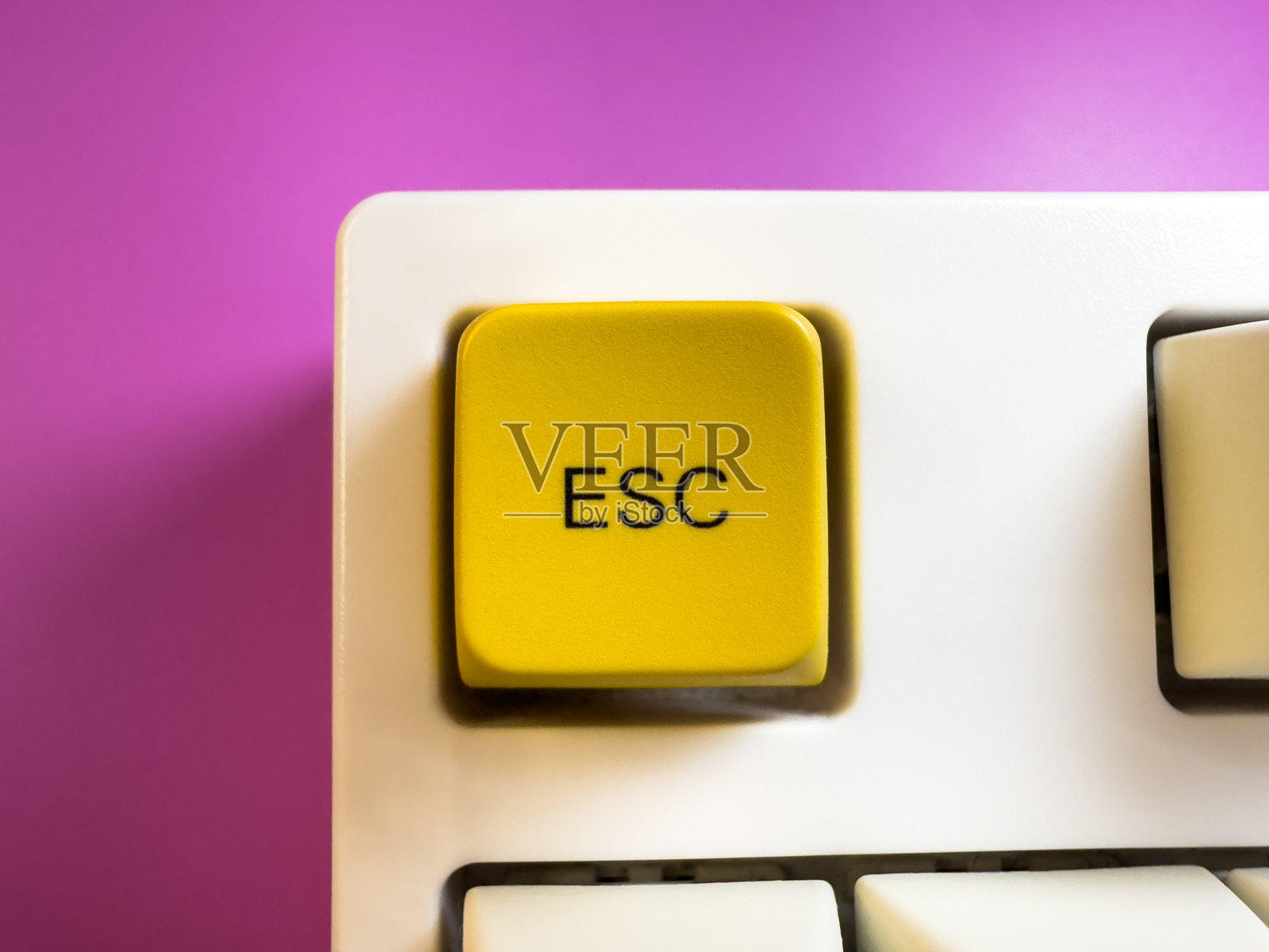 白色键盘上的大黄色Esc键，背景为紫色，平铺，留白空间照片摄影图片
